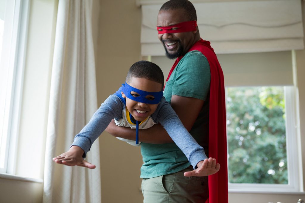 Son and father pretending to be a superhero at home